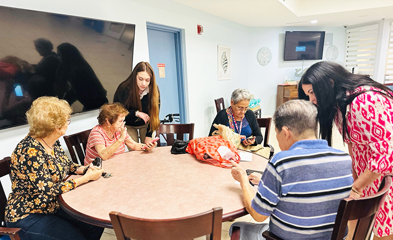 Anabella Alvarez (standing left), CyberWise Seniors founder, guides seniors through sending text messages at the Palmer House in Miami Mar. 4, 2024. CyberWise Seniors strives to equip the elderly to independently and safely navigate technology.