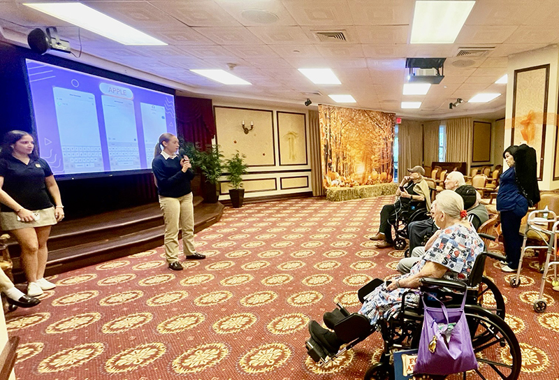 Anabella Alvarez (standing second from left), CyberWise Seniors founder, teaches seniors at The Palace Renaissance and The Palace Royale in Miami to independently and safely navigate technology Feb. 3, 2025.