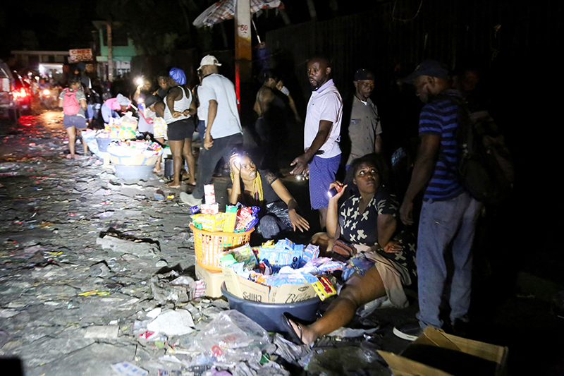 People sell goods on a street during a June 18, 2025, blackout in Port-au-Prince, Haiti's capital, after residents from a nearby town stormed a dam and cut power in protest over government inaction against gang violence in the country.