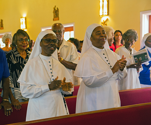 Sisters of the Daughters of Mary Mother of Mercy clap and sing during Mass at which Archbishop Thomas Wenski installed Spiritan Father Fidelis Nwankwo as the pastor of St. Philip Neri Church in Miami Gardens, June 22, 2025.