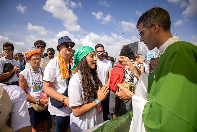 A priest distributes Communion to a young woman during a Mass closing the Jubilee of Youth in Rome’s Tor Vergata neighborhood Aug. 3, 2025.