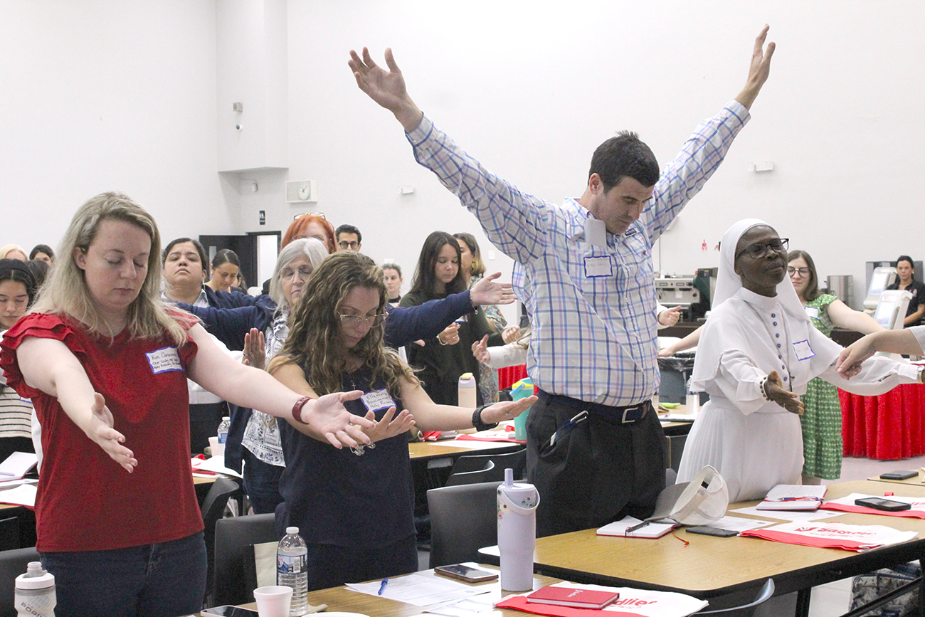 New teachers raise their arms during an activity at the New Teacher Orientation Aug. 4, 2025, held at Msgr. Edward Pace High in Miami Gardens, organized by the Office of Catholic Schools.