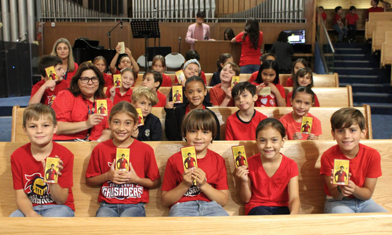 St. Louis Covenant School third grade teacher Anelise Foley (second row, left) and her students hold up prayer cards of St. Carlo Acutis during a "Canonization Celebration" held at their school in Pinecrest on Sept. 5, 2025.