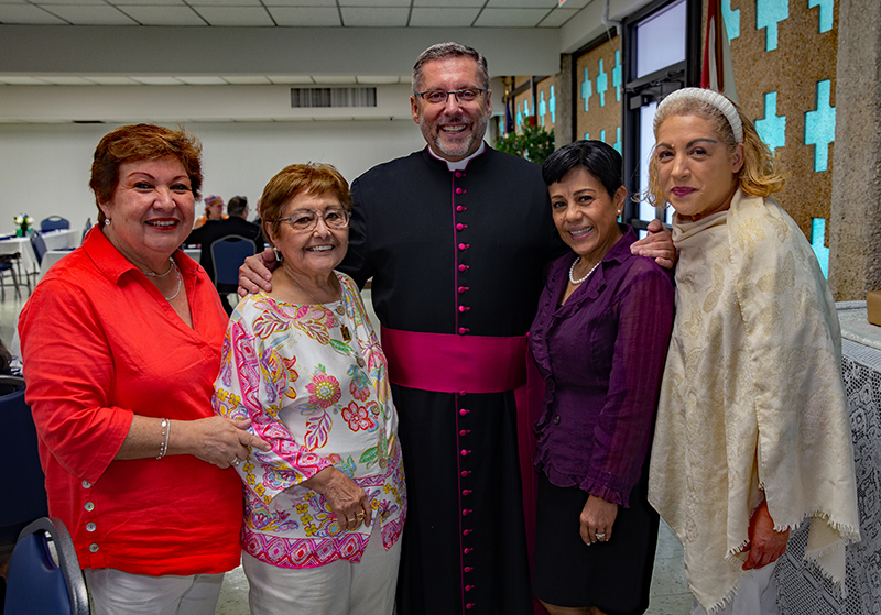 Pastoral Center employees Maite Lenoz, Maritza Maggio, Msgr. Dariusz Zielonka, archdiocesan chancellor for canonical affairs, Mayra Rossell and Zulley Mar Vidal pose for a photo at a reception after Mass Sept. 7, 2025, when Archbishop Thomas Wenski installed Msgr. Zielonka as pastor of St. Pius X Church in Fort Lauderdale.