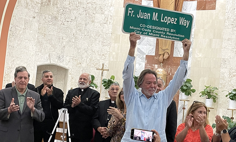 Frank Lengyel, a parishioner at Sts. Peter and Paul Church in Miami, raises the Fr. Juan M. López Way street sign during the unveiling ceremony honoring Fr. López, the church's pastor for 34 years. In conjunction with Miami-Dade County, the city of Miami co-designated a section of SW 9th Avenue in front of the parish in honor of the priest. Due to rain, the event took place inside the church on September 12, 2025.