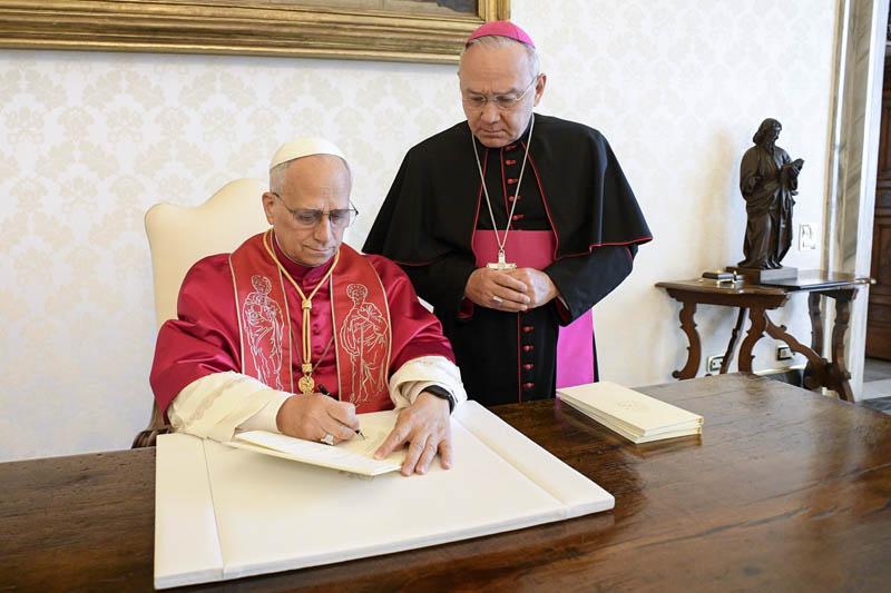 Pope Leo XIV signs his first apostolic exhortation, "Dilexi Te" ("I Have Loved You"), in the library of the Apostolic Palace at the Vatican Oct. 4, 2025, the feast of St. Francis of Assisi, as Archbishop Edgar Peña Parra, the substitute secretary for general affairs at the Vatican Secretariat of State, looks on. The exhortation will be released Oct. 9. (CNS photo/Vatican Media)