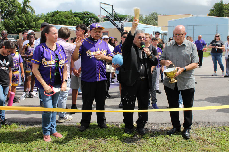 Auxiliary Bishop of Miami Enrique Delgado blesses with holy water the newly renovated athletic field at St. Michael the Archangel School, Miami, on Sept. 28, 2025. Accompanying him in the moment (from left) is St. Michael the Archangel School Principal Lisette Reina-Naranjo, St. Michael the Archangel Parish Pastor Father Elvis Gonzalez, and Deacon Rafael Maria Calvo.
