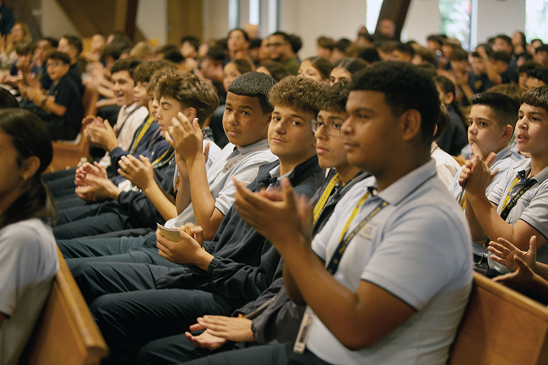 Middle school students from Our Lady of the Lakes School in Hialeah applaud Dario Mobini, director of WorldYouthDay.com, for bringing the relic of St. Carlo Acutis from Assisi, Italy, to St. David Church in Davie, Oct. 10, 2025.