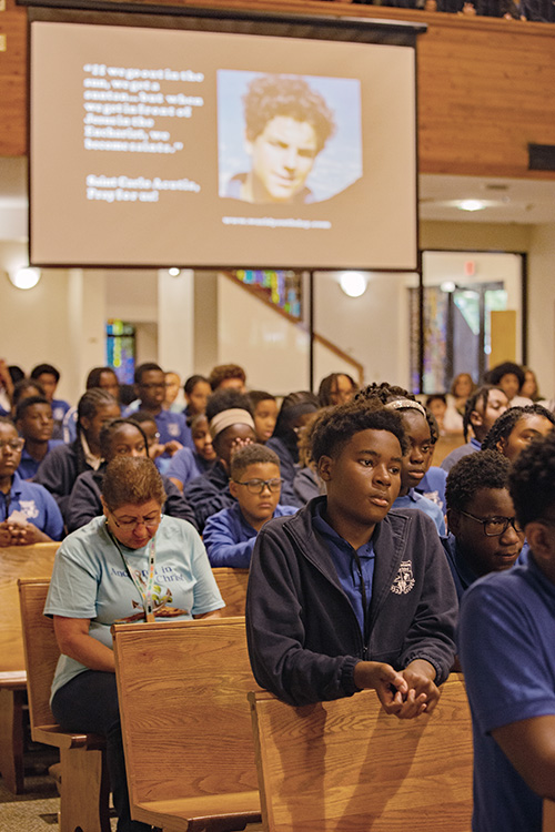 Scofield Jean, 13, a seventh grader at St. Bartholomew School in Miramar, prays with other students during a Holy Hour in the presence of a first-class relic of St. Carlo Acutis, the first millennial saint, at St. David Church in Davie, Oct. 10, 2025.
