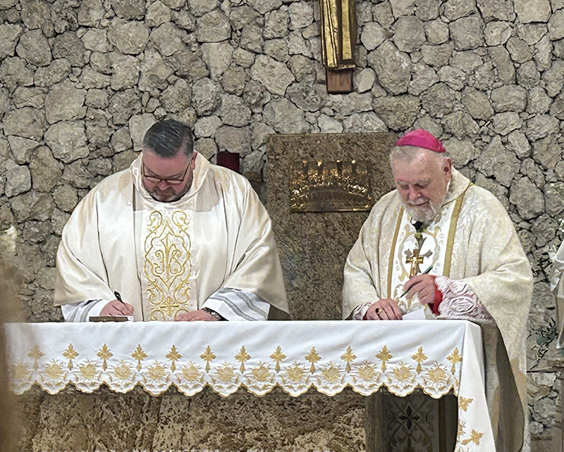 Archbishop Thomas Wenski, right, and Father Ryan Saunders sign documents declaring Father Saunders pastor of St. David Parish in Davie, Oct. 12, 2025.