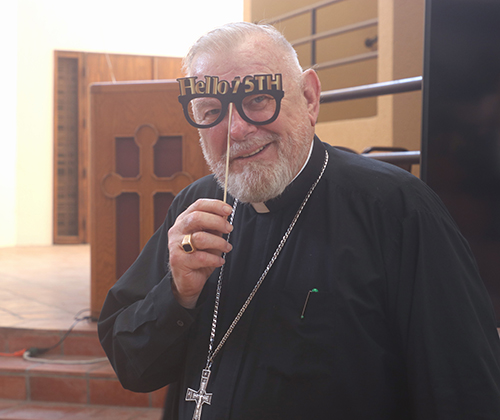 With masquerade glasses that read “Hello 75,” Archbishop Thomas Wenski gets ready to celebrate his birthday with Archdiocese of Miami Pastoral Center staff Oct. 20, 2025.