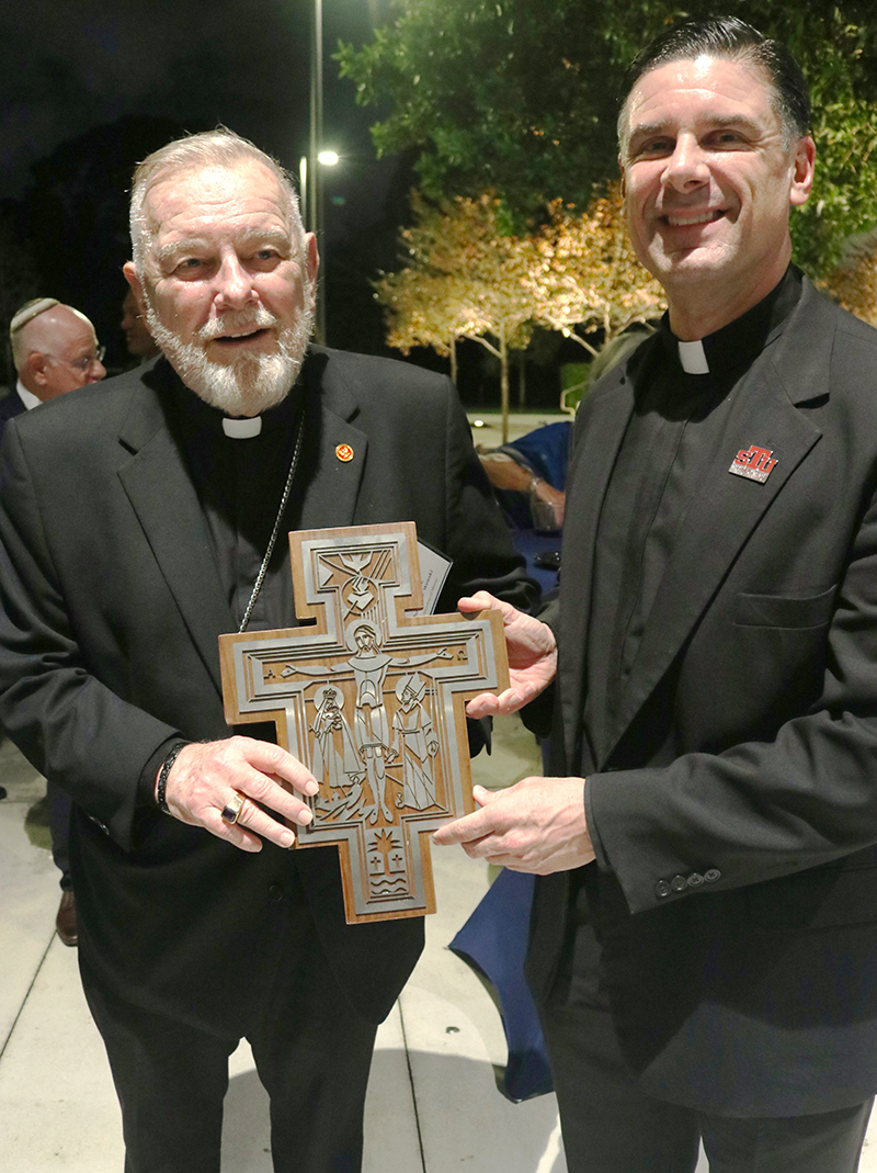 At a reception marking the 60th anniversary of Nostra Aetate at St. Thomas University on Oct. 20, 2025, Father Rafael Capó, vice president for ministry and mission at St. Thomas University, presented Archbishop Thomas Wenski with a birthday gift on behalf of the university.