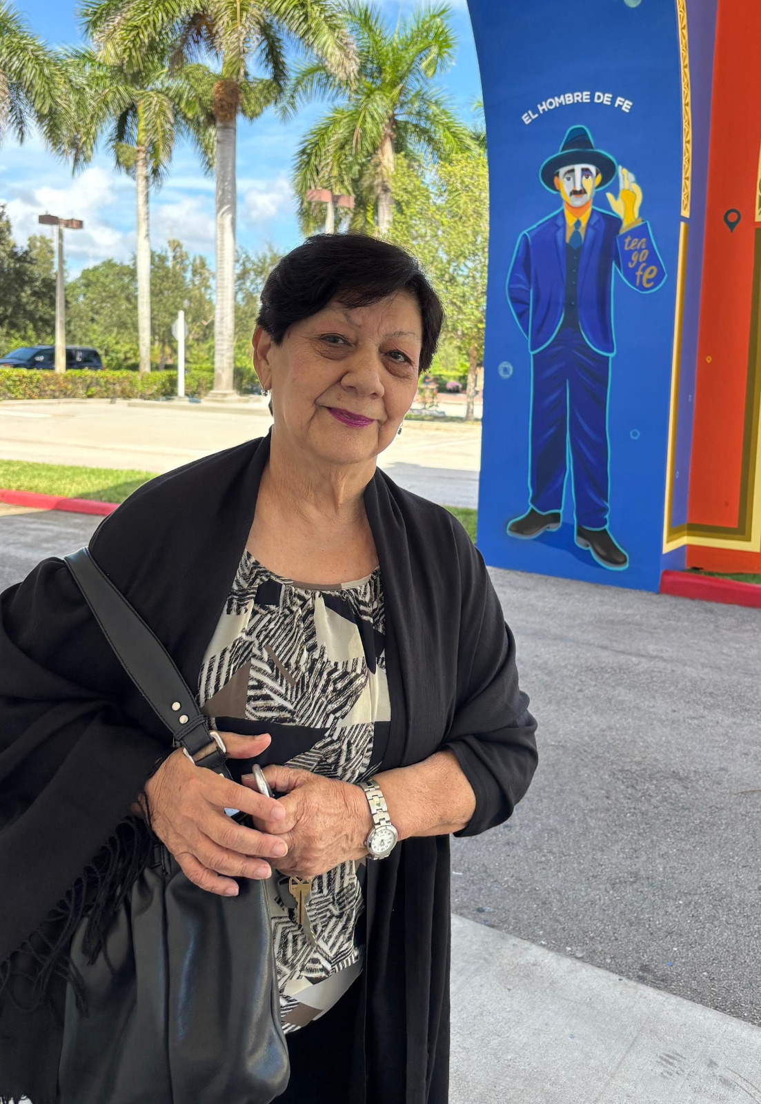 Ana Padrón, a parishioner at St. Katharine Drexel in Weston, poses in front of an image of Blessed José Gregorio Hernández called "El hombre de fe" (The Man of Faith), located in the parish. Venezuelan artist Eduardo Sanabria created the image in homage to the new saint, who will be canonized on October 19, 2025.