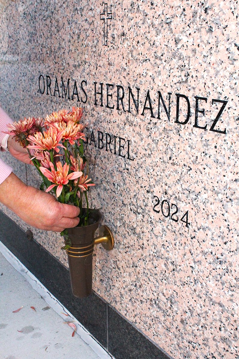 Marta Garcia places flowers at the tomb of her uncle, Gabriel Oramas Hernandez, who is buried in the Resurrection Mausoleum Complex at Our Lady of Mercy Catholic Cemetery in Doral. Archbishop Thomas Wenski blessed the complex Nov. 14, 2025.