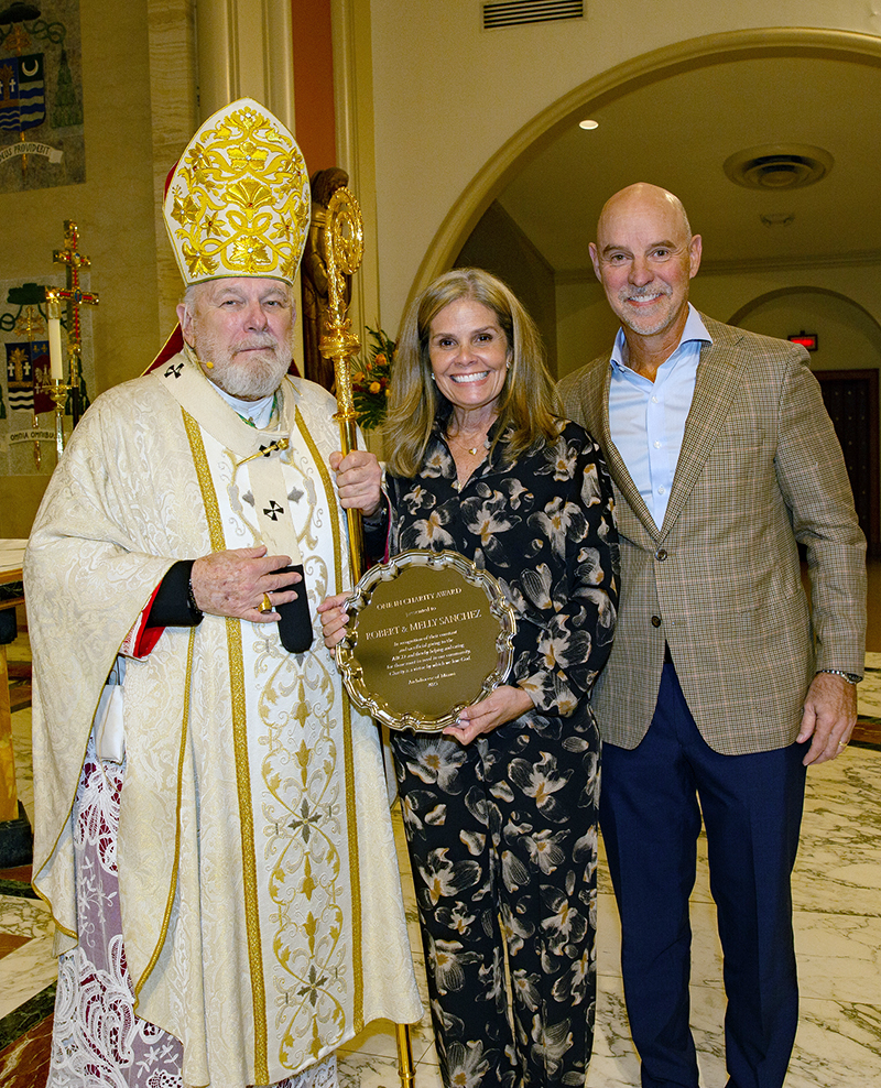 Archbishop Thomas Wenski presents Robert and Melly Sanchez, of St. Augustine Church in Coral Gables, with the 2025 One in Charity award during the annual Thanks-for-Giving Mass hosted by the archdiocesan Office of Development to honor those who contribute faithfully to the ABCD. The Mass was celebrated Nov. 22, 2025 at St. Mary Cathedral in Miami.
