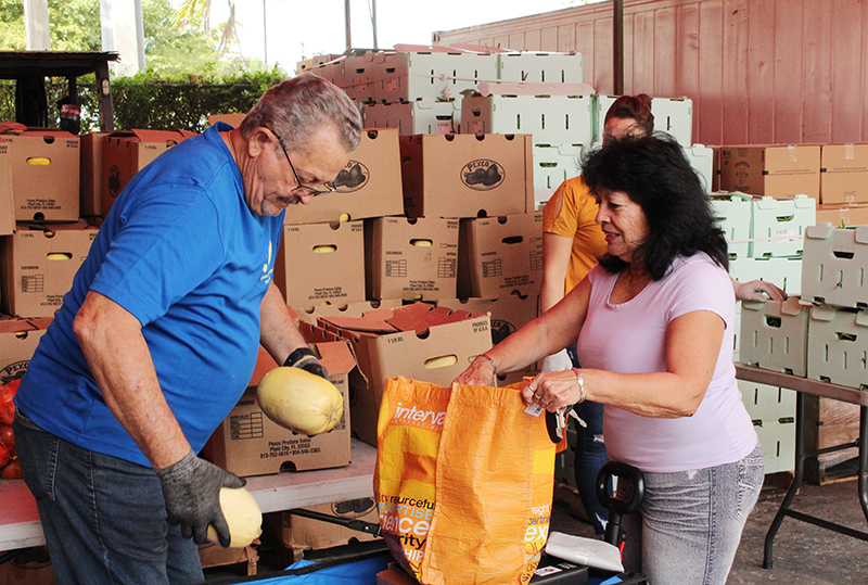 Leyla Scaparone, a client of Catholic Charities of Miami Matthew 25 Food Pantry, opens her bag to receive spaghetti squash from Ezequiel Cajete, a volunteer at Matthew 25, Nov. 24, 2025, at the pantry’s warehouse in Miami. Matthew 25 has appealed to the public for donations to help feed those in need during the holiday season.