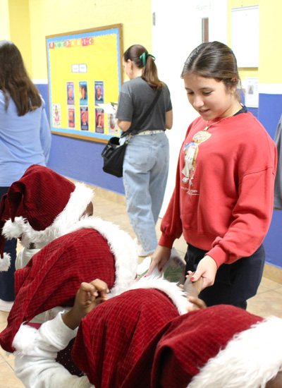 Ali Medina, a freshman at Lourdes Academy, says good-bye to children from Catholic Charities Notre Dame Child Development Center during a holiday event on Dec. 16, 2025. On that day, over 200 children at Notre Dame received gifts donated by the Lourdes Academy community.