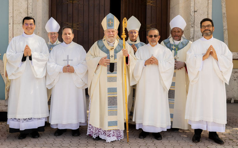 The ordination group of new deacons pose with Archbishop Thomas Wenski for a photo following the Mass of Ordination Dec. 13, 2025 at St. Mary Cathedral, Miami. From left to right in the photo are Deacon Christian David Mendietta; Bishop Gregg Caggianelli; Deacon Ramon Carlos Palacio; Archbishop Thomas Wenski; Bishop Silvio Baez Ortega; Deacon Teodoro Gonzalez; Bishop Pierre Andre Dumas; and Deacon Gustavo Adolfo Roversi.