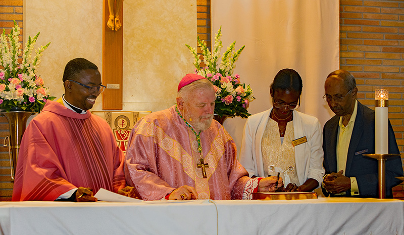 During the 75th anniversary Mass of Holy Redeemer Church in Miami celebrated on Dec. 14, 2025, Archbishop Thomas Wenski installed Father Emmanuel Essiet as the church's pastor. In the photo, from left, is Father Essiet, Archbishop Wenski, Sandra Diadhion and Patrick Range signing documentation naming Father Essiet as pastor.