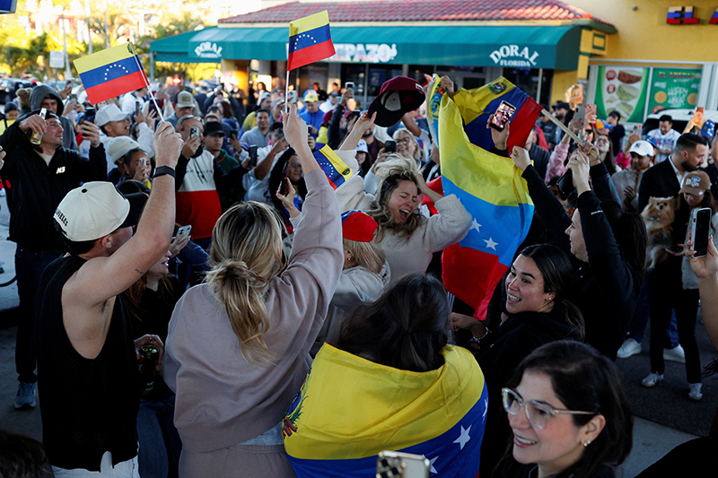 People hold Venezuelan flags on the streets of Miami Jan. 3, 2026, as they react to the news after U.S. President Donald Trump said the U.S. has struck Venezuela and captured its President Nicolas Maduro.