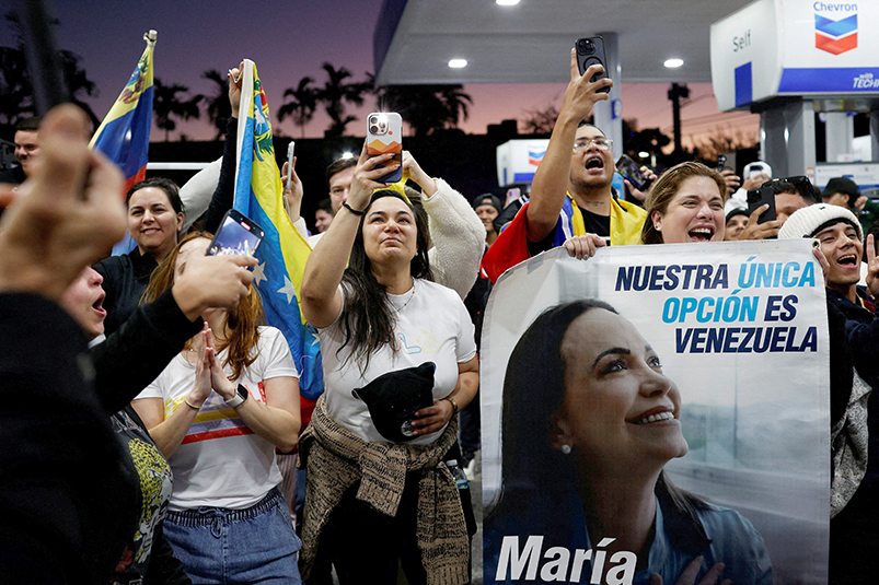 A woman holds a banner depicting Venezuelan opposition leader and Nobel Peace Prize laureate Maria Corina Machado as people react in Miami Jan. 3, 2026, to the news that U.S. forces struck Venezuela and captured its President Nicolas Maduro.