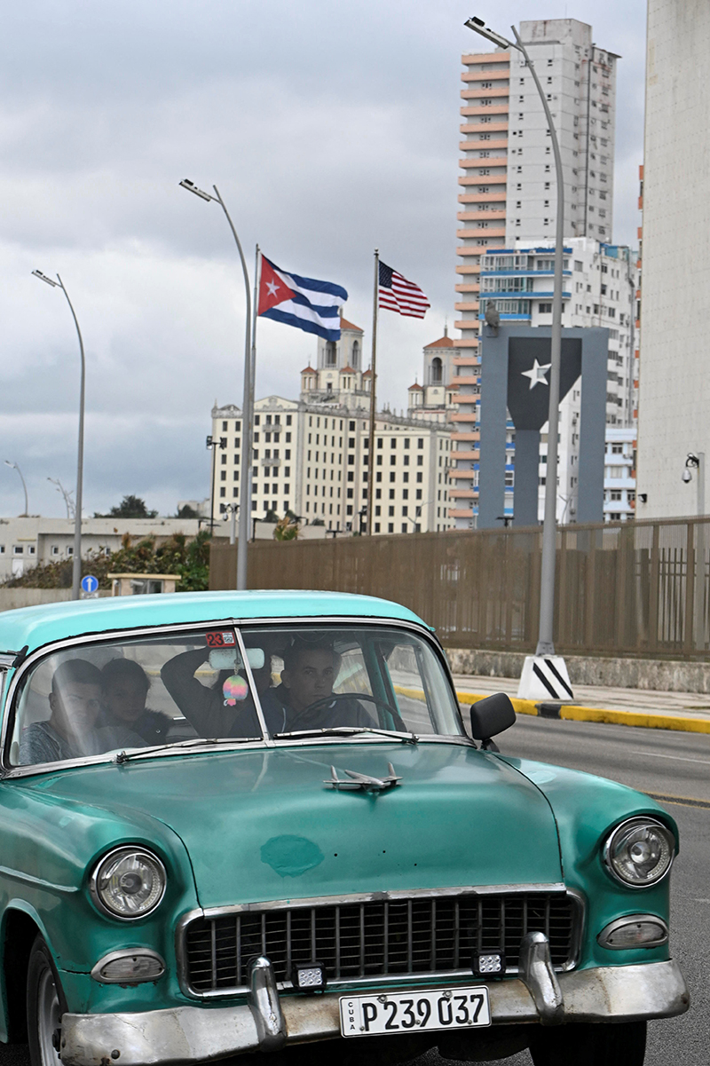 Un automóvil clásico pasa junto a una bandera cubana y una estadounidense en La Habana, mientras cubanos de todos los sectores de la sociedad entran en modo supervivencia, enfrentando apagones aparentemente interminables y el alza de los precios de los alimentos, el combustible y el transporte, mientras Estados Unidos amenaza con imponer un estrangulamiento económico a la nación gobernada por el comunismo. Cuba, 30 de enero de 2026.