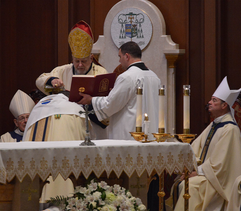 Archbishop Thomas Wenski pours sacred oil over the head of Bishop-Elect Manuel de Jes&uacute;s Rodr&iacute;guez during his ordination Mass Feb. 24, 2026. At left is his predecessor Bishop-Emeritus Gerald M. Barbarito and at right is his former shepherd, Bishop Robert Brennan of Brooklyn.