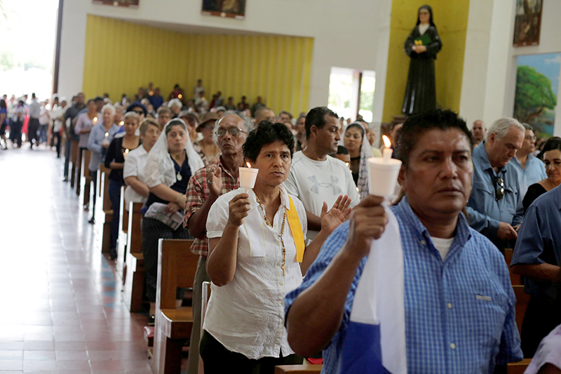 Feligreses sostienen velas mientras oran durante una misa en la Catedral Metropolitana de Managua, Nicaragua, el 28 de octubre de 2018, en apoyo al obispo auxiliar nicaragüense Silvio José Báez Ortega y para exigir la liberación de presos políticos. El obispo Báez, quien enfrentó amenazas de muerte y acoso por parte del régimen de Ortega, fue forzado al exilio en 2019.