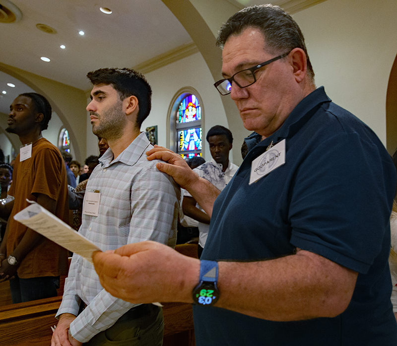 Amado Vidal, sponsor, places his right hand on shoulder of catechumen, Kevin Gonzalez Esperon, of Prince of Peace Church. 947 catechumens from 110 parishes signed the Book of the Elect during two ceremonies Feb. 22 at St. Mary's Cathedral in Miami.