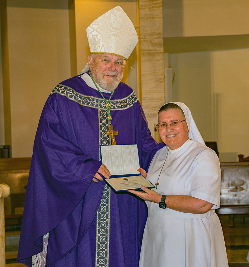 Archbishop Thomas Wenski gifts certifcate to Sister Sadeh Abed Alnour, FMA, Salesians for 25 years. Archbishop Thomas Wenski celebrated Mass for Archdiocese of Miami consecrated life members and four jubilarians Mar. 8, 2026.