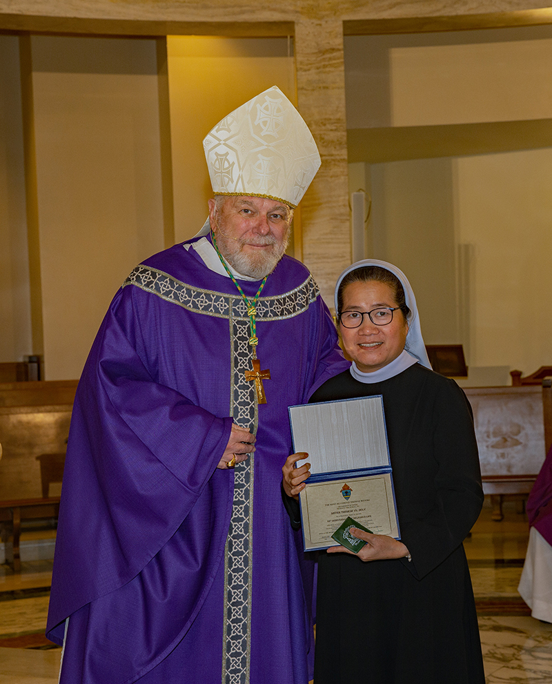 Archbishop Thomas Wenski gives certificate to Sister Therese Vu, Daughters of Our Lady of Visitation for 25 years. Archbishop Thomas Wenski celebrated Mass for Archdiocese of Miami consecrated life members and four jubilarians Mar 8, 2026.