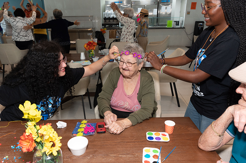 Miami-Dade Community College students Ana Quevedo.far lett, and Nubia Nipper, far right, enjoy some craft activities with Josephina Fornells and during a recent special event for local senior citizens sponsored by Catholic Charities of the Archdiocese of Miami.