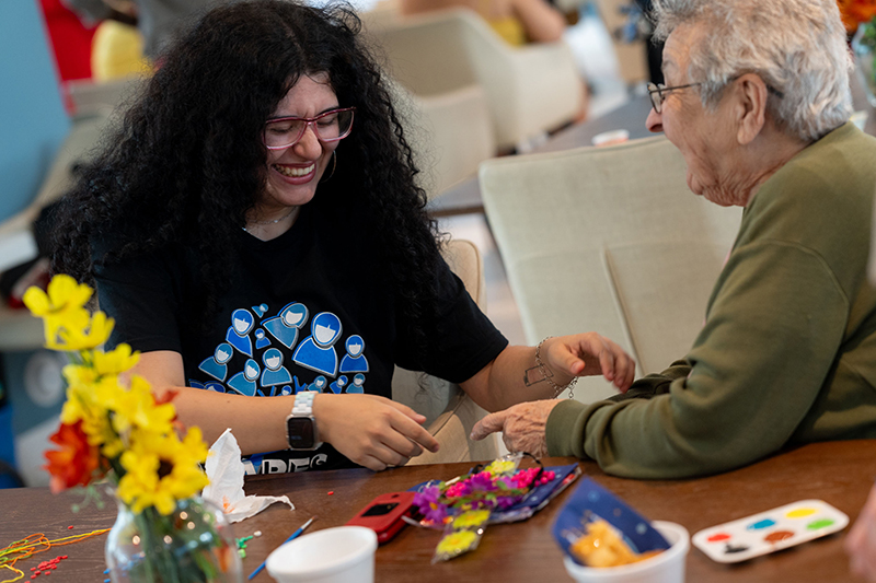 Miami-Dade Community College student Milena Manrique helps a senior citizen with a craft bracelet during a special event for local senior citizens sponsored by Catholic Charities of the Archdiocese of Miami.