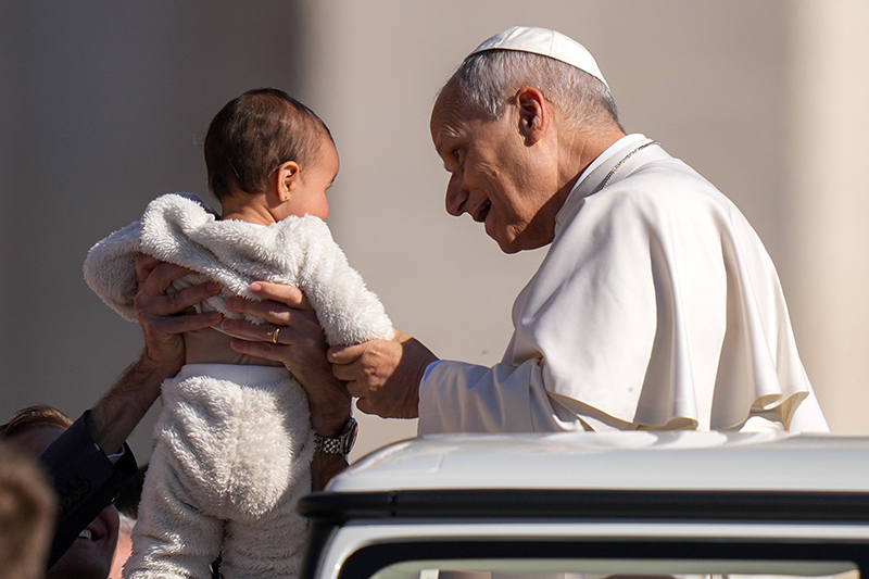 Pope Leo XIV greets a child from the popemobile while riding around St. Peter’s Square at the Vatican before his weekly general audience April 8, 2026. (CNS photo/Lola Gomez)