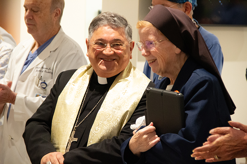 Auxiliary Bishop Enrique Delgado (second from left) and Sister Elizabeth Worley, Archdiocese of Miami chancellor for administration and chief operating officer (COO), enjoy the April 21 dedication of the revamped surgical lobby at HCA Florida Mercy Hospital in Miami. The surgical waiting room honors the hospital’s sponsors, the Sisters of St. Joseph of St. Augustine, as well as Sister Worley, former chair of the Mercy Hospital Board.