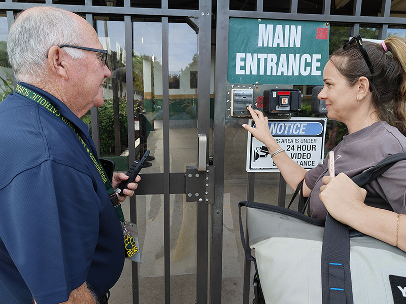 A visitor uses the intercom system at the main entrance of St. David Catholic School to contact the school office before being granted access. The school uses controlled entry, video surveillance and visitor check-in procedures as part of its campus security measures.