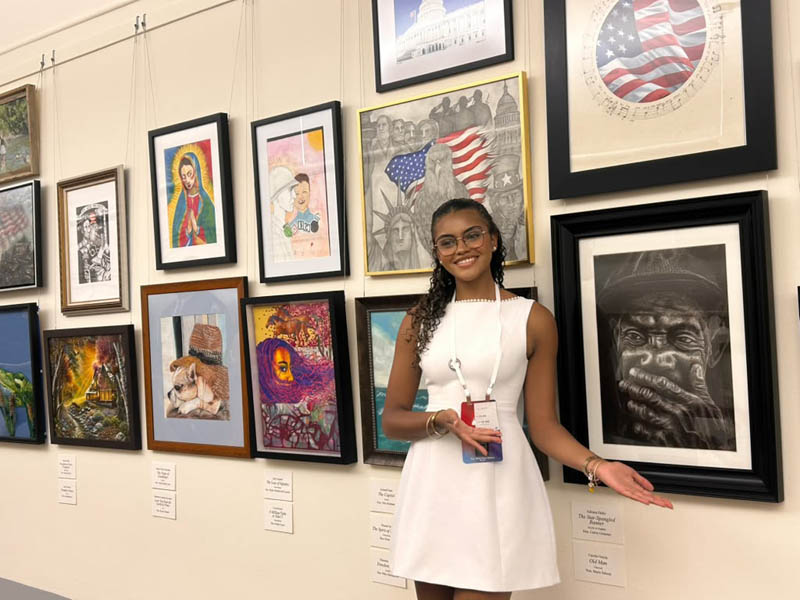 Immaculata-La Salle High School (ILS) graduate Camila Garcia poses with her charcoal portrait "Old Man,” which was honored with first place in the Congressional Art Competition for Florida's 27th Congressional District. Her painting will be on display in the U.S. Capitol's Cannon Tunnel for the next year. Camila attended the contest exhibit’s opening reception June 25, 2026 in Washington, D.C.