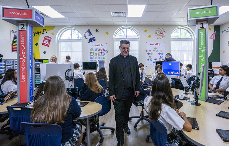 On the first day of school Aug. 11, 2026, Father Manuel “Manny” &Aacute;lvarez greets students at St. Theresa Catholic School in Coral Gables. More than 900 students returned to St. Theresa for the school’s 101st year of education. “(The school is) asleep during the summer, and now the children fill the hallways with their noise, their joy and their laughter,” said Father &Aacute;lvarez, pastor of the school’s parish, Church of the Little Flower.