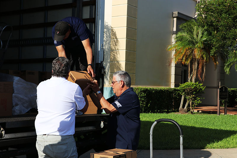 At bottom left, Thomas Falcon, president of the Kiwanis Club of Little Havana, and Mel Carmona, one of the chairmen for the Kiwanis school distribution project, unload boxes at St. Mary’s Cathedral School in Miami Aug. 18, 2026. The Archdiocese of Miami was a sponsor for Kiwanis of Little Havana's Back-to-School Project, which provided school supplies for students in underprivileged communities this August.