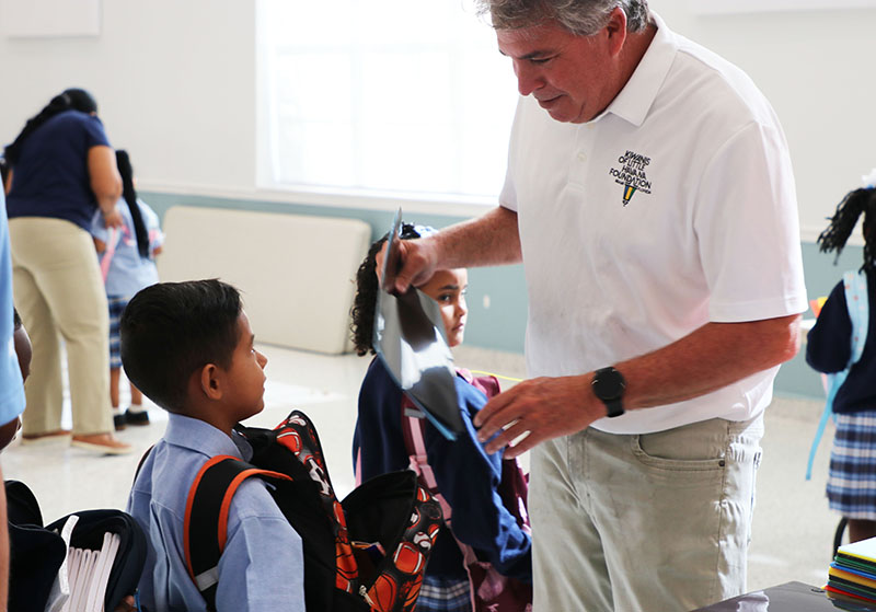 At right, Thomas Falcon, president of the Kiwanis Club of Little Havana, gives new folders to a student from St. Mary’s Cathedral School in Miami Aug. 18, 2026. The Archdiocese of Miami was a sponsor for Kiwanis of Little Havana's Back-to-School Project, which provided school supplies for students in underprivileged communities this August.