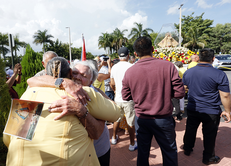 Wilma Pozo hugs a parishioner in front of the pilgrim image of Our Lady of Charity at Sacred Heart Parish in Homestead Aug. 22, 2026, the final stop of a 35-mile motorcade procession through Miami-Dade County. Parishioners welcomed the image – a symbol of the Virgin Mary’s presence in South Florida – with prayers, rosaries, flowers and Cuban flags.