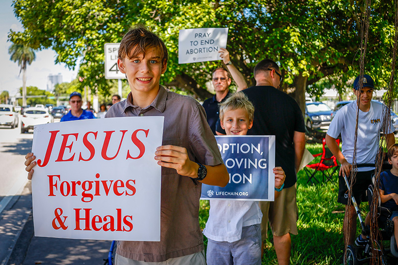 Dmitri Ross, 14, poses with families from the ARCH Angels of South Florida Catholic homeschool community advocating for respect for human dignity during the annual Miami Life Chain display across US 1 on Respect Life Sunday, Oct. 4, 2026.
