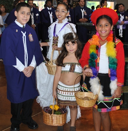Wearing costumes depicting the different regions and ethnic groups of Peru, children who are members of the Brotherhood of El Se�or de los Milagros present the offertory gifts at Mass. From left: Randal Calle, wearing the brotherhood's purple robes; Ximena Sakay representing Peru's coast ("costa"); Karyme Delgado, representing the jungle ("selva"); and Jacqueline Pavon, representing the sierra ("sierra").