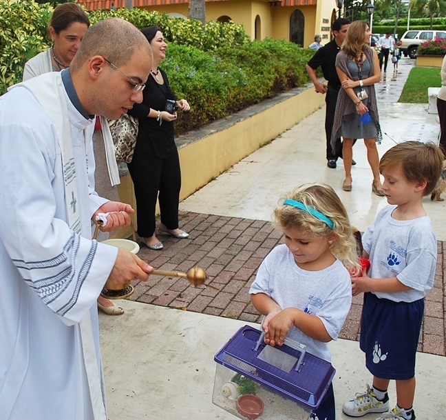 Father Luis Rivero, parochial vicar, blesses the pet of one of St. Agnes Academy's littlest students.