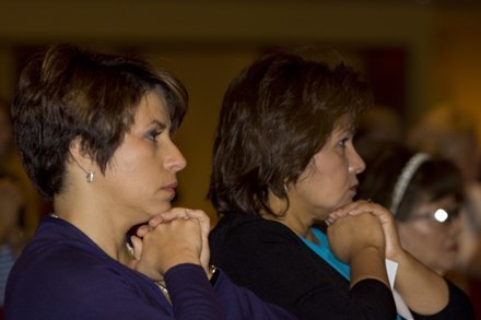 Ivonne Diaz, left, and Miriam Ato of the finance office pray during the Mass.