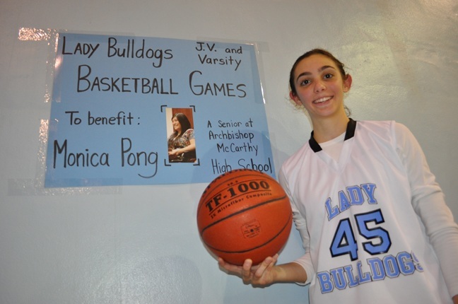 Briana Pulido poses in front of a sign she made to promote the fundraiser.