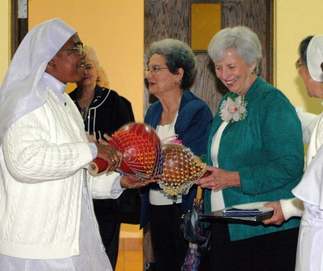 A member of the Daughters of Mary, Mother of Mercy, shows golden jubilarian Sister Helene Kloss, an Adrian Dominican, how to play a gourd, one of several typical Nigerian musical instruments played by the Nigerian sisters during the reception which followed the annual Mass in honor of consecrated life.