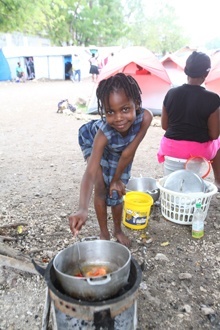 A child cooks a meal at an earthquake refugee tent city in Port-au-Prince.