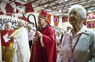 Archbishop Thomas Wenski passes Franciscan Sister Marie Schramko, assistant principal, as he processes into the gym for the Mass marking the start of Cardinal Gibbons High School's 50th year.