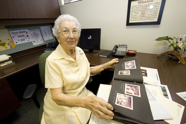 Sister Marie Schramko looks over the scrapbook she created showing the growth of Cardinal Gibbons High School over the years, from the time there were no buildings - but classes still went on - to the fully-developed campus that exists today.